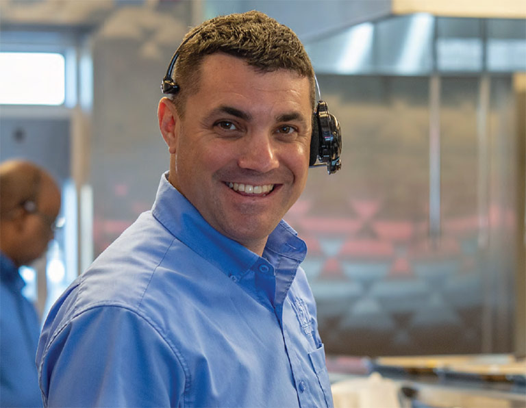 A smiling Habit Burger & Grill manager with headset